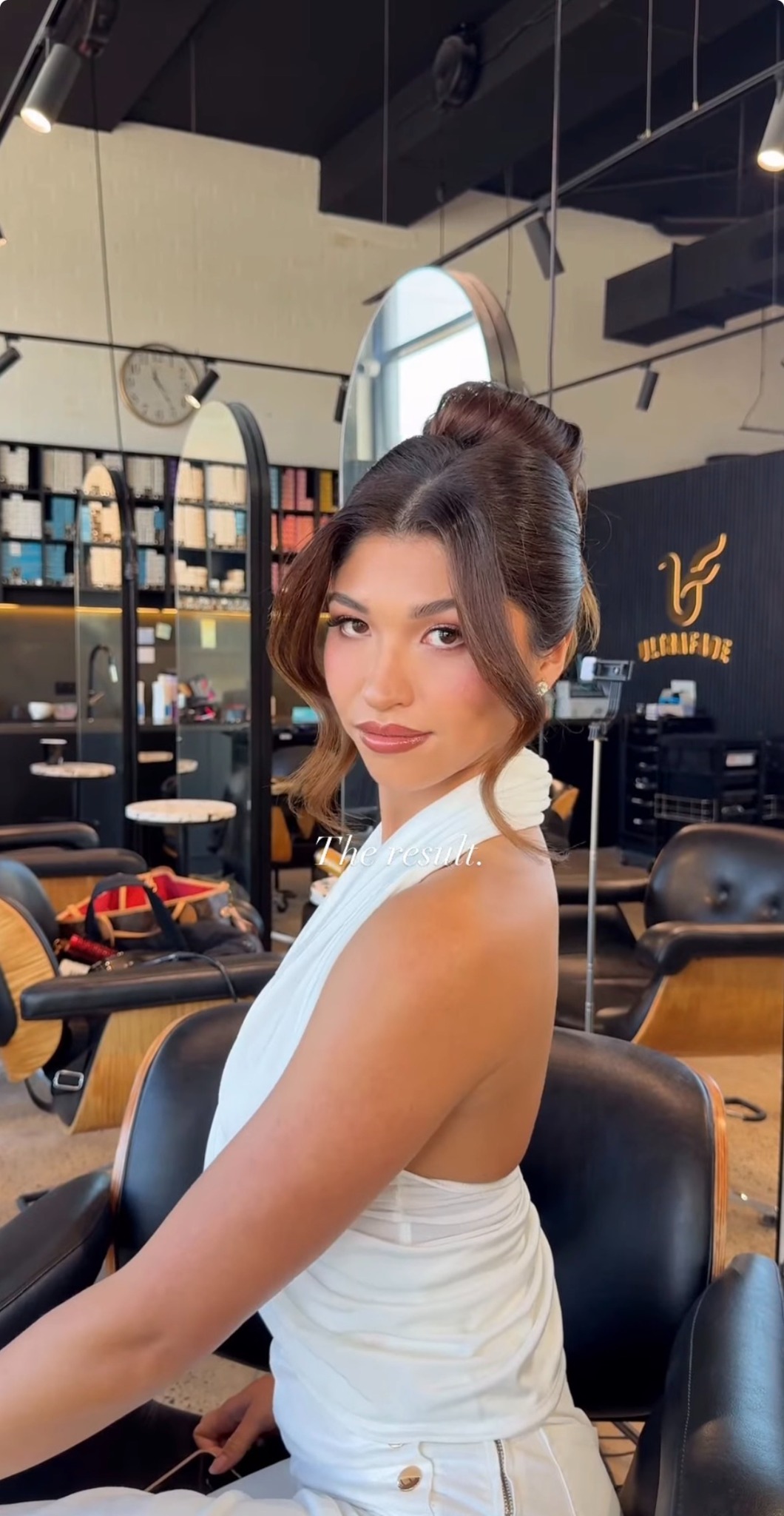 A client wearing a sculpted updo and white halter top in the salon